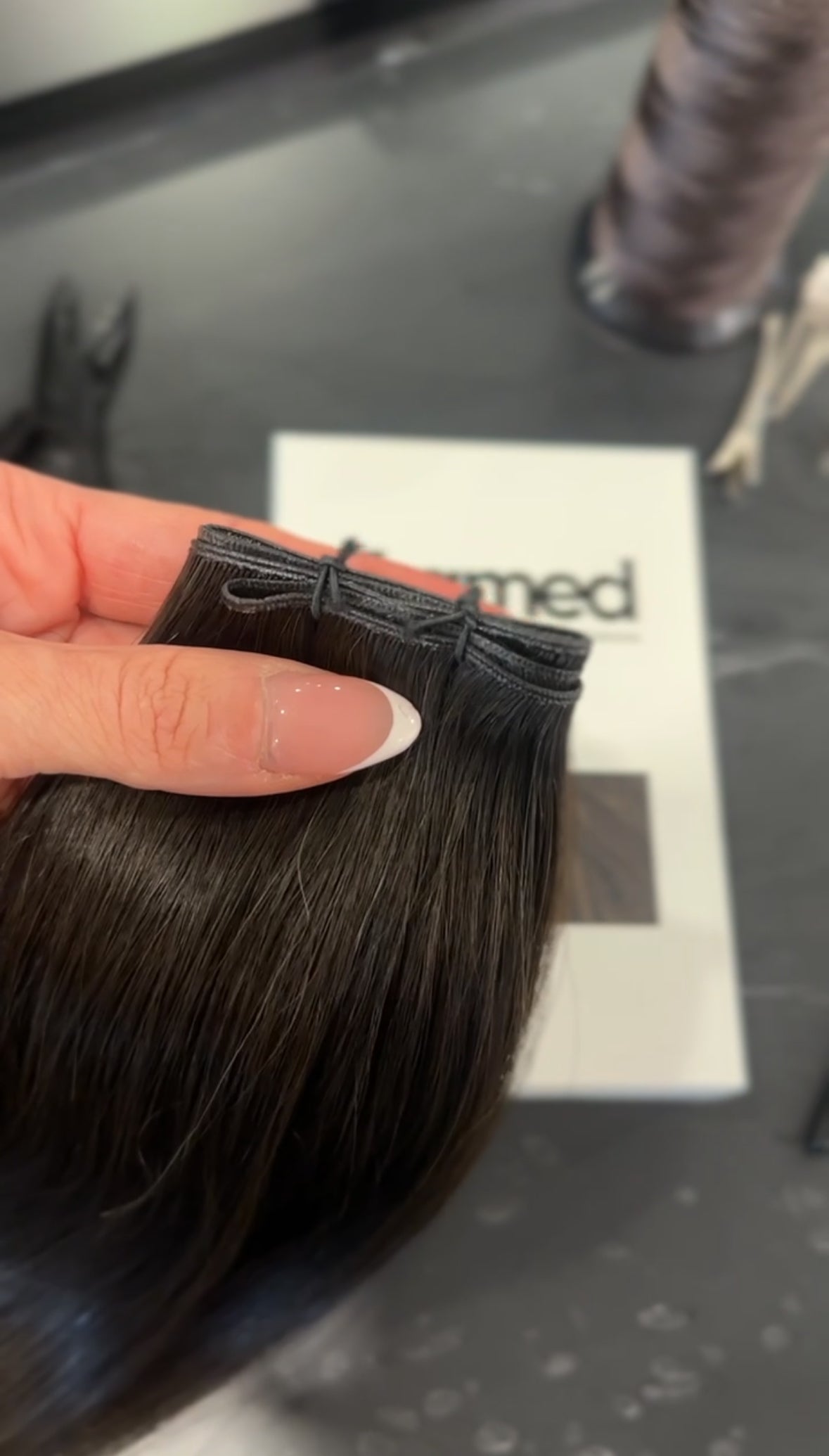 Zoom in of Genius Weft for professional use #3 Mocha shades in a hair salon in montreal with thread and hair clipper 