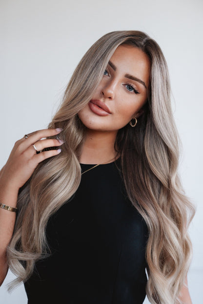 Gros plan sur les extensions à clips invisibles, nuance Russian Nova — mélange homogène et texture soyeuse, Framed Hair Extensions Montréal. / Close-up of invisible clip-in extensions in shade Russian Nova, seamless blend and silky texture Framed Hair Extensions Montreal.